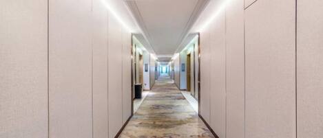 Un pasillo de hotel con piso alfombrado, puertas a ambos lados e iluminación en el techo.