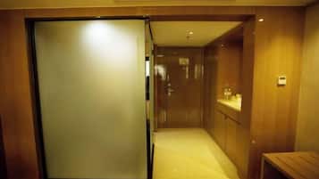 A hotel corridor with a sliding door, a small bench, and a counter with toiletries.