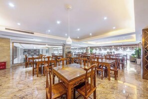 A spacious dining area with multiple wooden tables and chairs, a marble floor, and pendant lighting. - Feng Ya Hotel (Jinjiang)