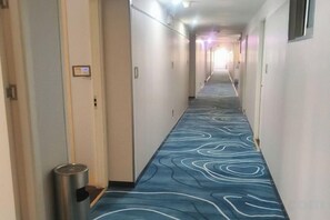 A hotel corridor with a patterned carpet, doors on both sides, and a trash bin. - Yongxing He'an Business Hotel (Yongxing)
