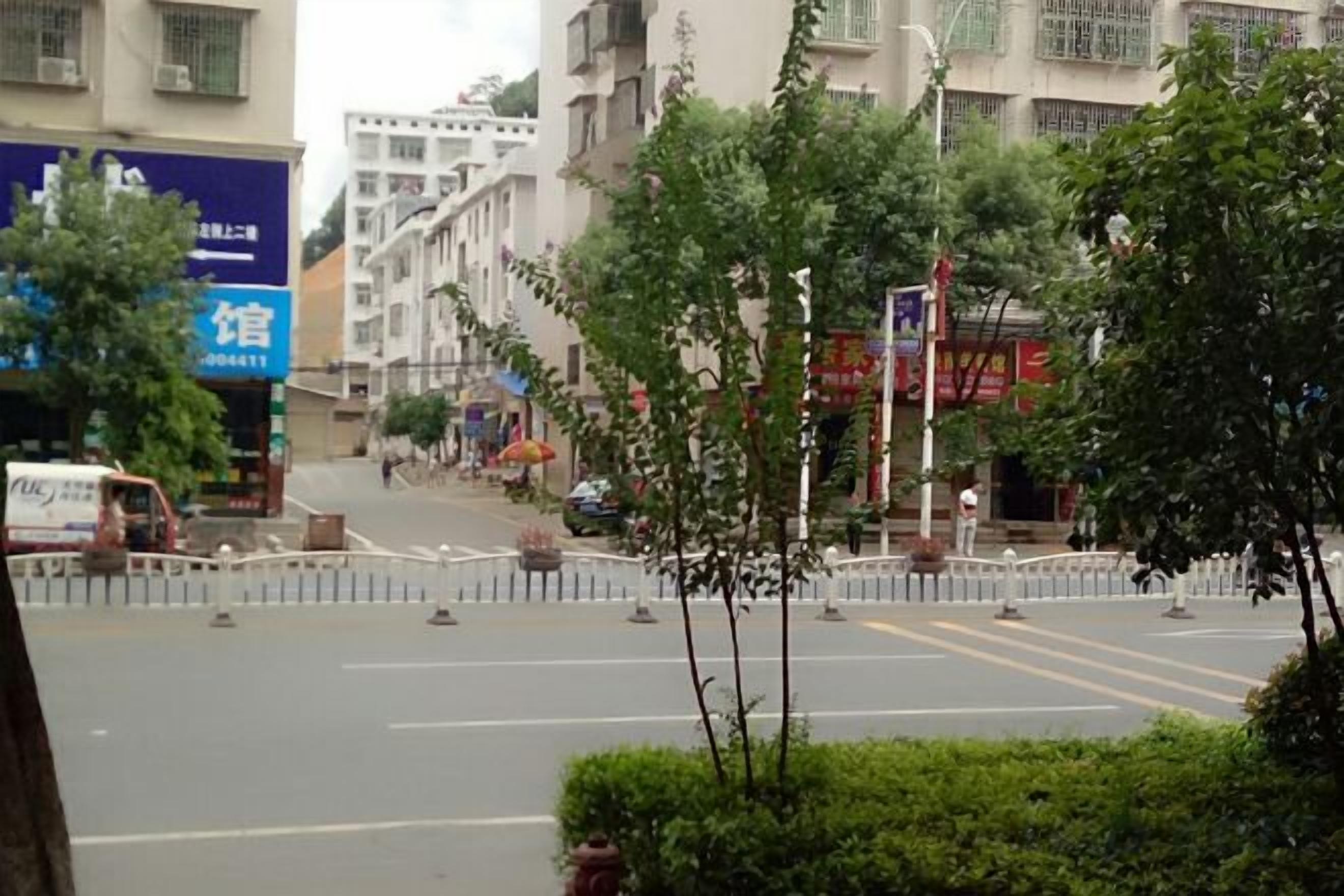 A street view with buildings, trees, and a clear sky.
