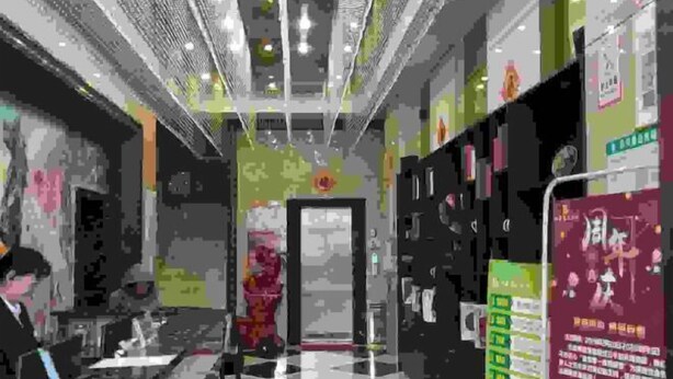Un hall de hotel con suelo a cuadros, una recepción y una escalera que sube a los pisos superiores.