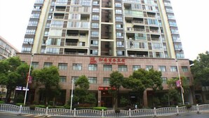 Un hotel de varios pisos con una entrada central, balcones en cada planta y un cartel que indica que es un hotel.