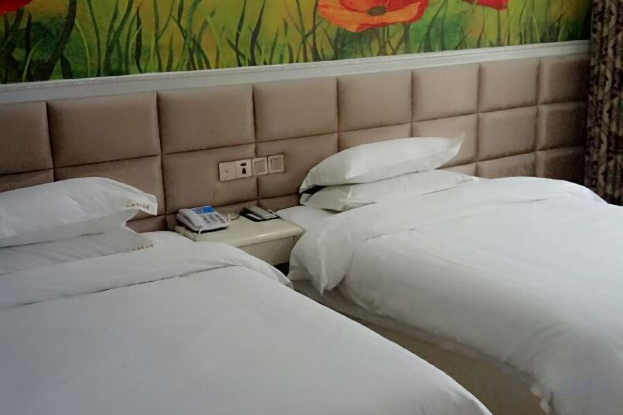 A hotel room with two beds, a headboard with a control panel, and a wall mural.