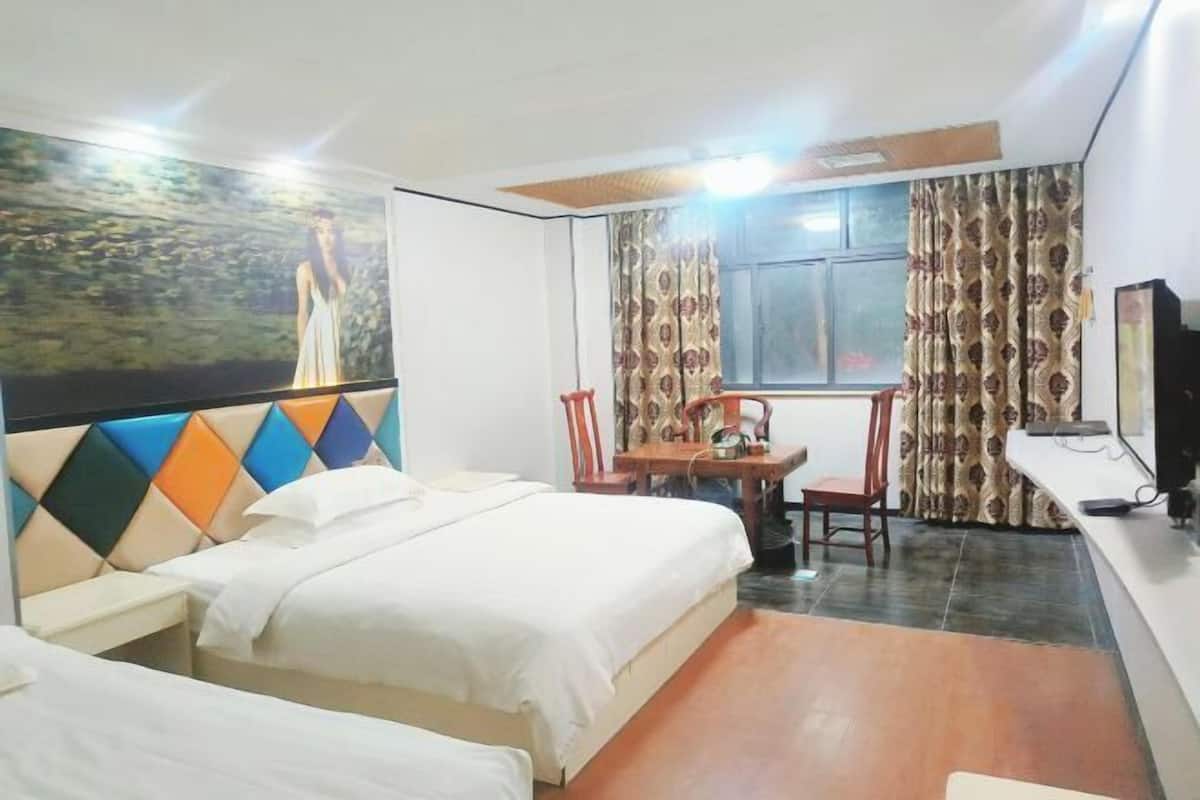 Een hotelkamer met een bed, bureau, stoel, televisie en raam met gordijnen.