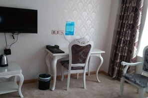 A small room with a TV, a desk, a chair, and a trash bin. - Yongxing He'an Business Hotel (Yongxing)