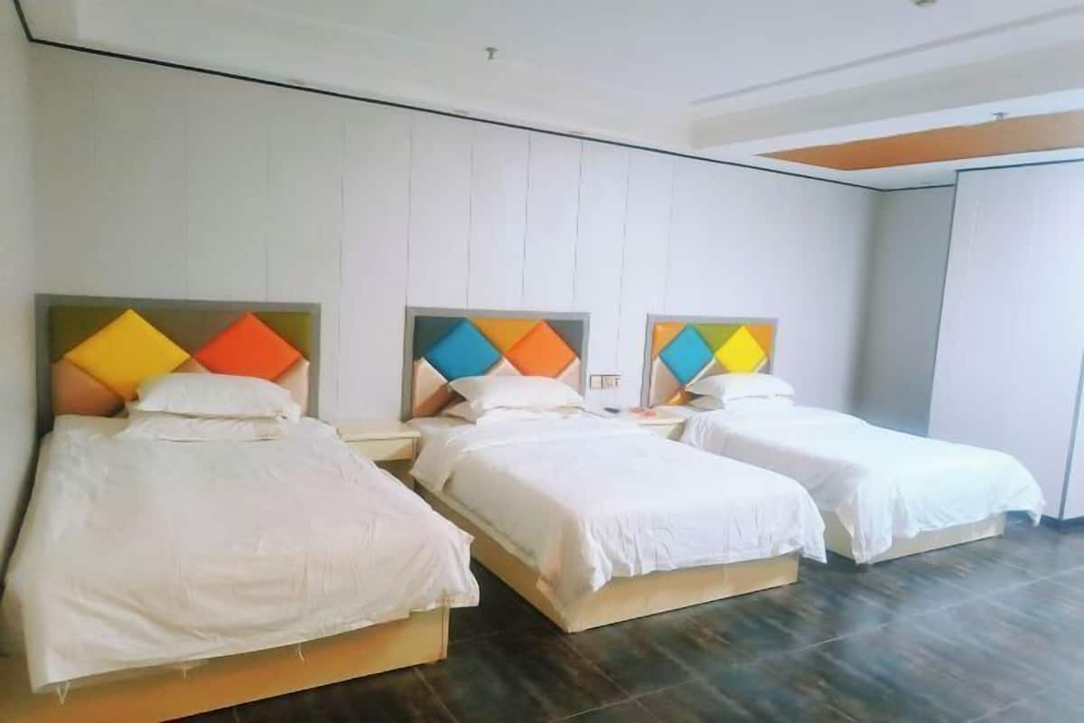 Drie eenpersoonsbedden met witte beddengoed, een modern hoofdbord en een kamer in neutrale tinten met een betegelde vloer.