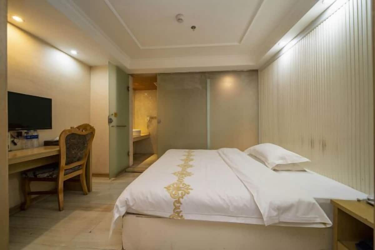 Een hotelkamer met een bed, een bureau, een stoel, een televisie en een kledingkast.