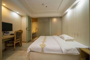 A hotel room with a bed, a desk, a chair, a television, and a wardrobe.