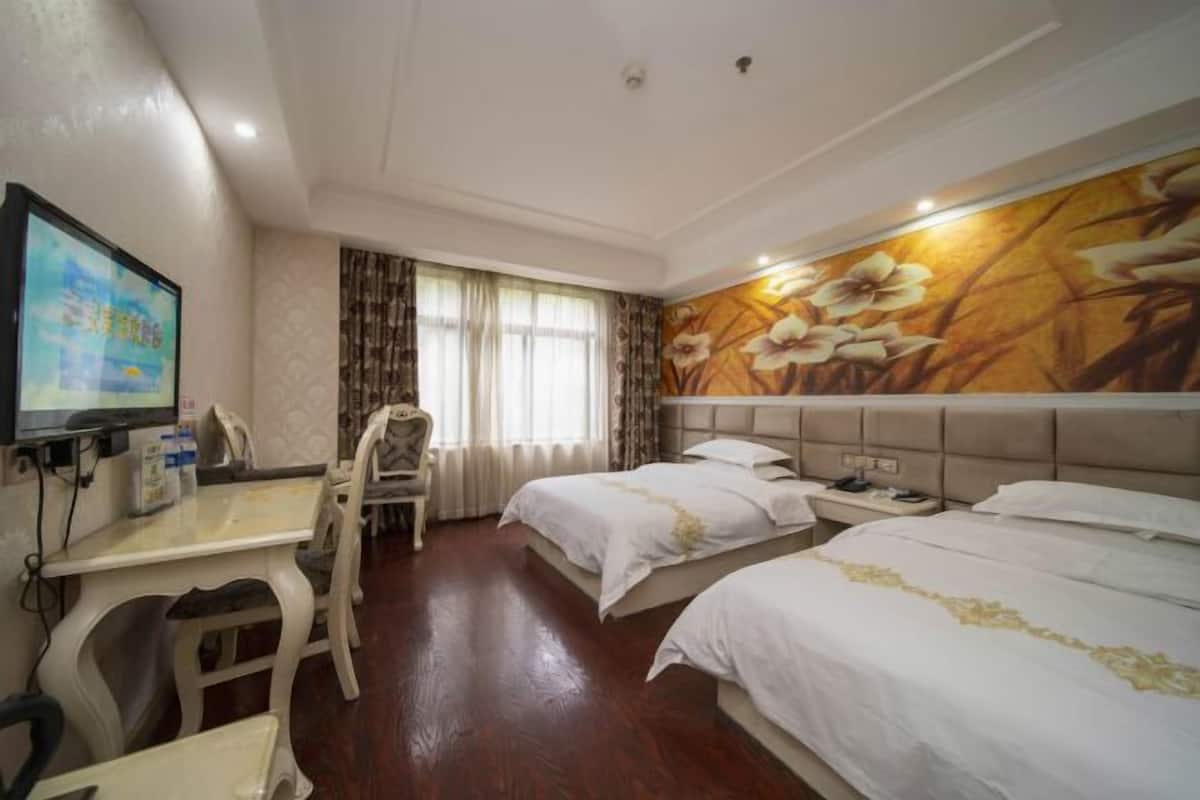 Een hotelkamer met een bed, nachtkastje, televisie en een bureau met stoel.