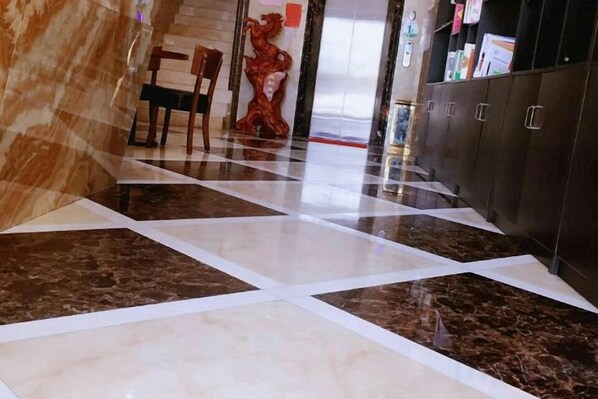 Un vestíbulo de hotel con piso de mármol, una recepción y una estatua.