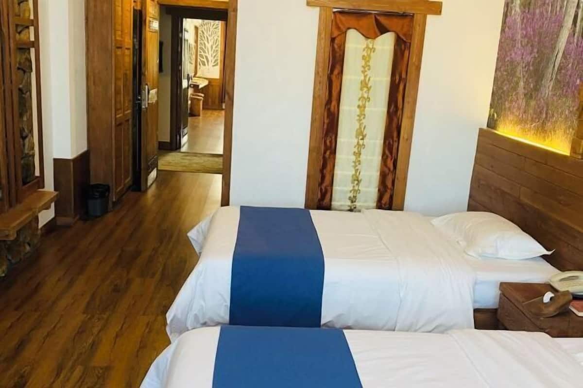 Ein Hotelzimmer mit zwei Betten, Holzboden, einem Holzkopfstück und einem Gemälde an der Wand.