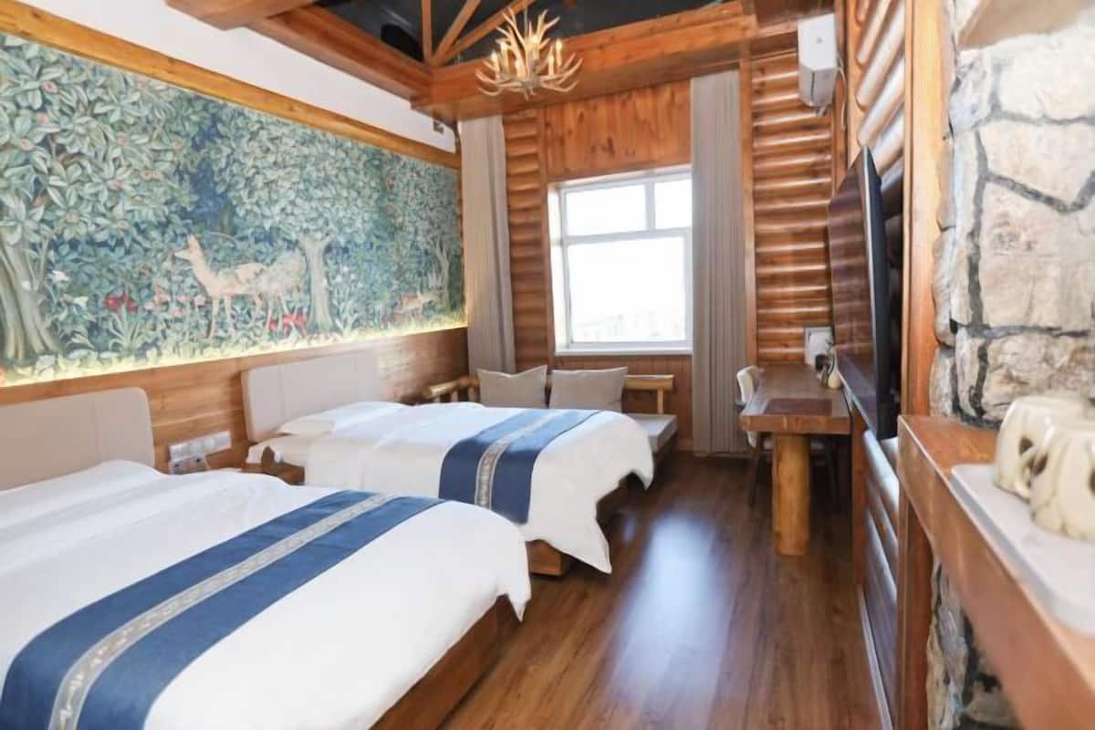 Ein Zimmer mit zwei Betten, einem Wandgemälde, einer Steinwand und einer Holzbalkendecke.