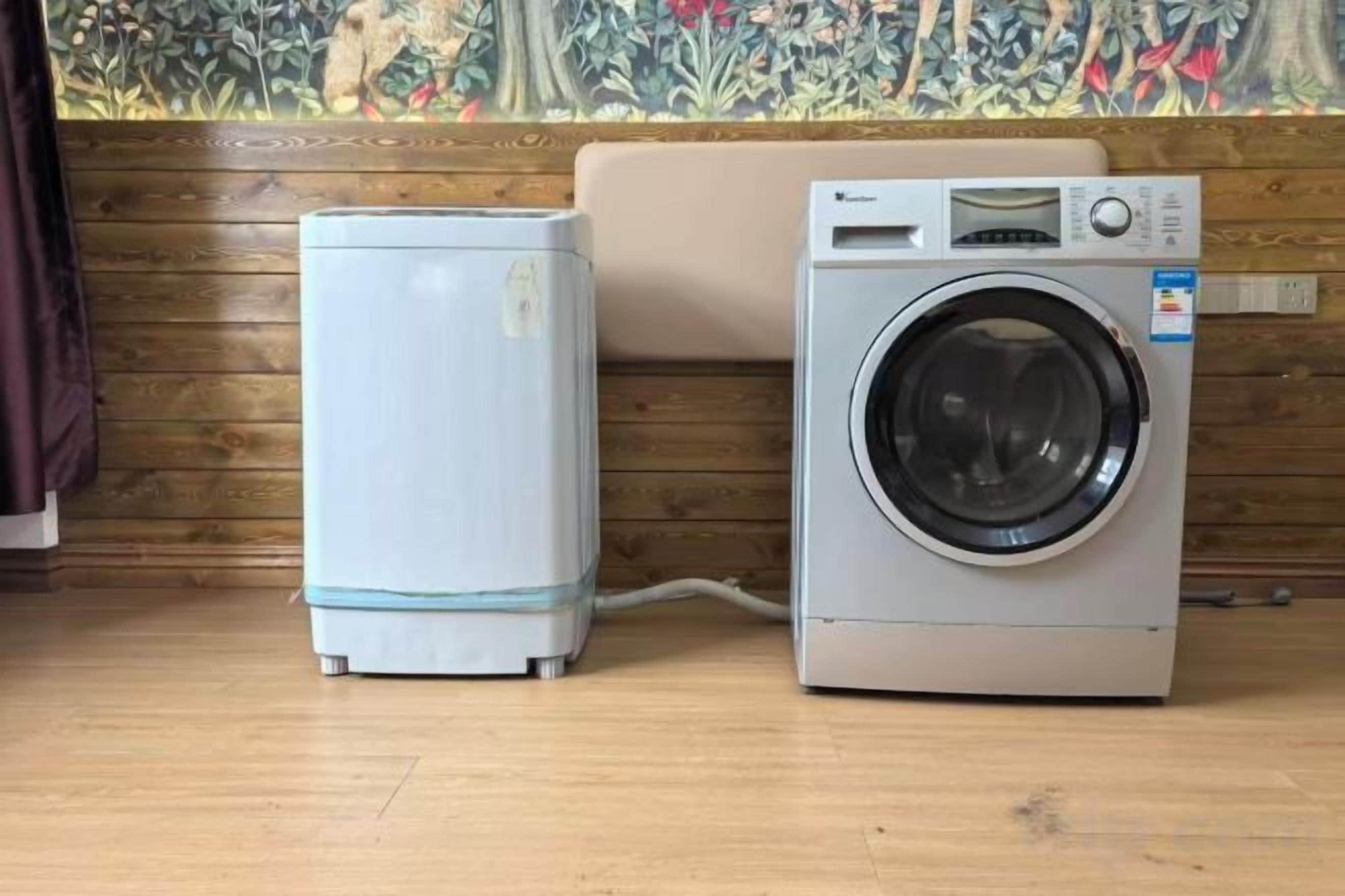 A washing machine and a dryer side by side on a wooden floor with a wooden wall and a mural in the background.