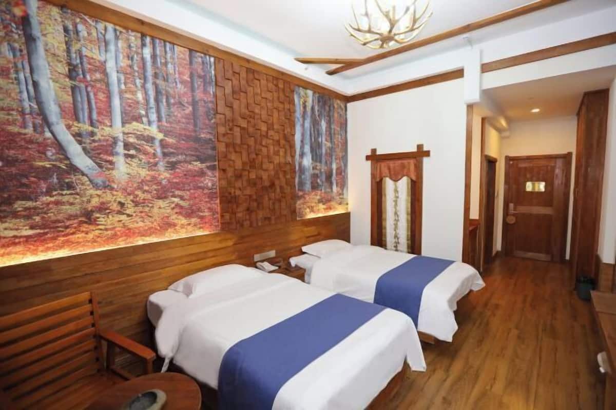 Ein Zimmer mit zwei Betten, einer Holzbank, Wandmalerei und einer Holztür.