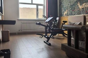 Habitación con una caminadora, un banco y un radiador.