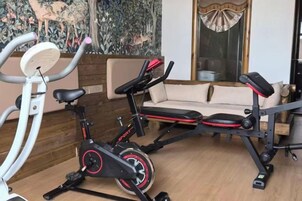 Un gimnasio en casa con una bicicleta estática, otra bicicleta de ejercicio y una banca.