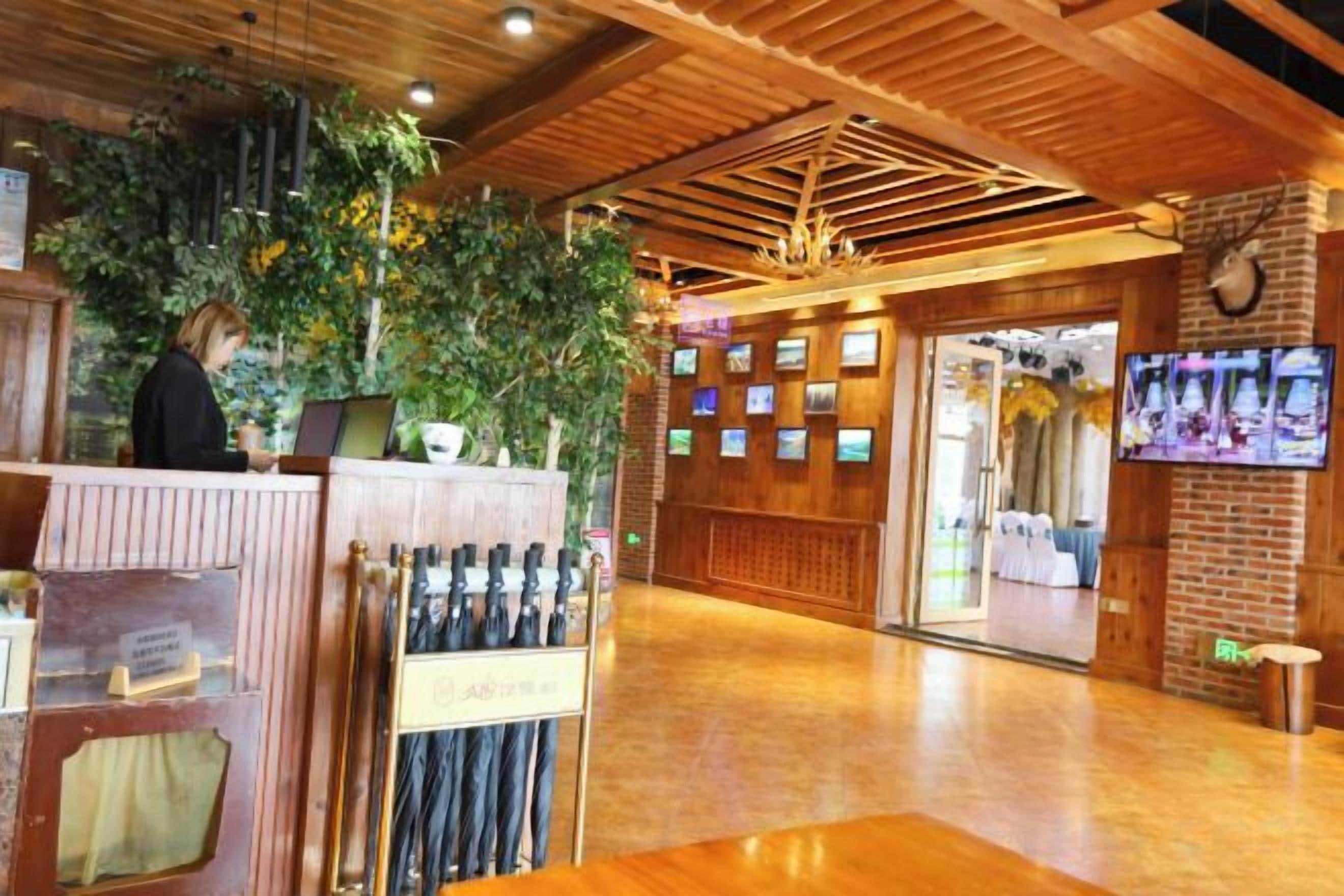 A reception area with a wooden ceiling, a reception desk, a plant, and a wall with framed pictures.