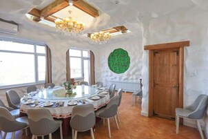 A round dining table with chairs, a chandelier, and a wooden door.