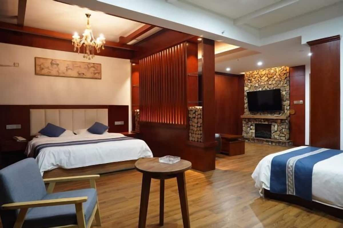 Ein Hotelzimmer mit zwei Betten, einem Fernseher, einem Kamin und einer Kristallleuchtre.'