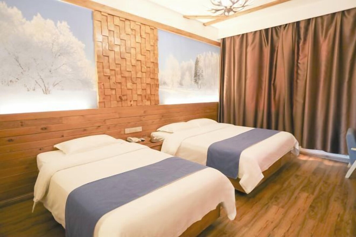 A room with two beds, a brick wall, a window with a snowy landscape view, and a curtain.