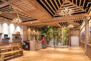 Un intérieur en bois comprenant un comptoir d’accueil, des bancs et une grande fenêtre donnant sur la forêt.