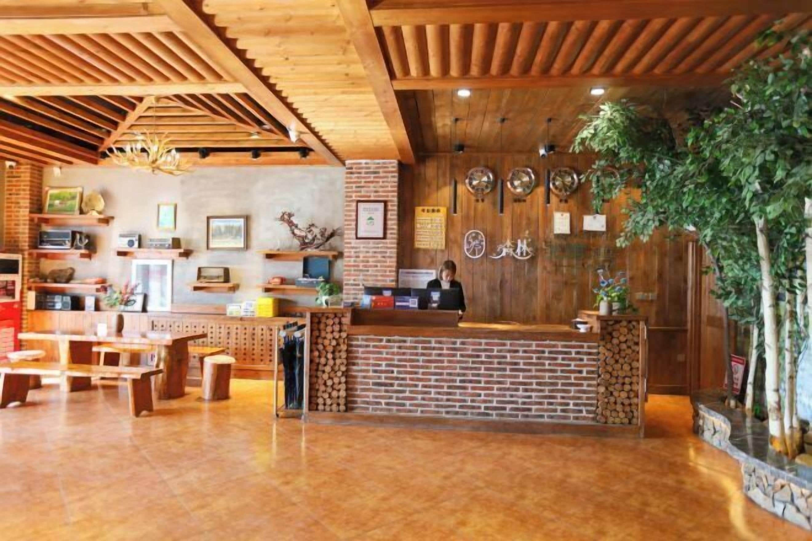 A wooden interior with a reception desk, benches, and a brick wall.