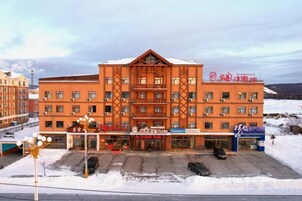 A multi-story hotel with a central atrium, a parking lot, and a snow-covered landscape in the background.