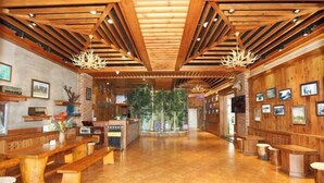 A spacious lobby with wooden benches, a brick fireplace, and framed pictures on the walls. - Forest Snow Hotel (Genhe)
