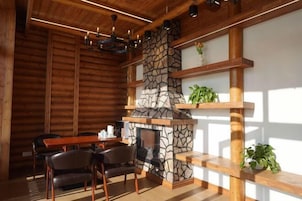 Un interior de cabaña acogedor, con chimenea de piedra, estantes de madera y comedor.