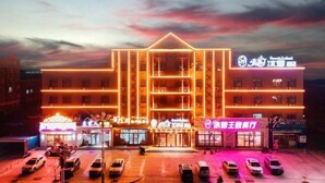 A multi-story hotel with a prominent entrance, multiple balconies, and a parking lot with several cars. - Forest Snow Hotel (Genhe)