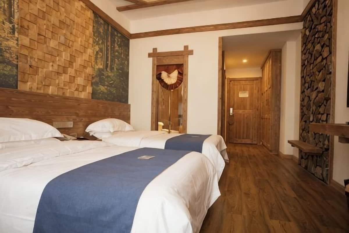 Ein Hotelzimmer mit zwei Betten, Holz-Kopfteilen, einer Steinwand und Holzboden.