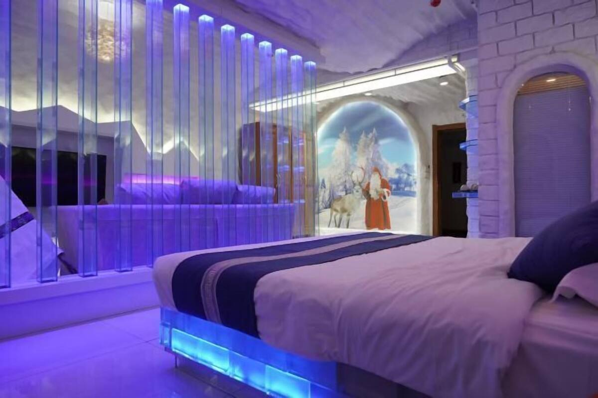 Ein Schlafzimmer mit einem Bett, einem Fenster mit vertikalen Jalousien und einem Wandgemälde.