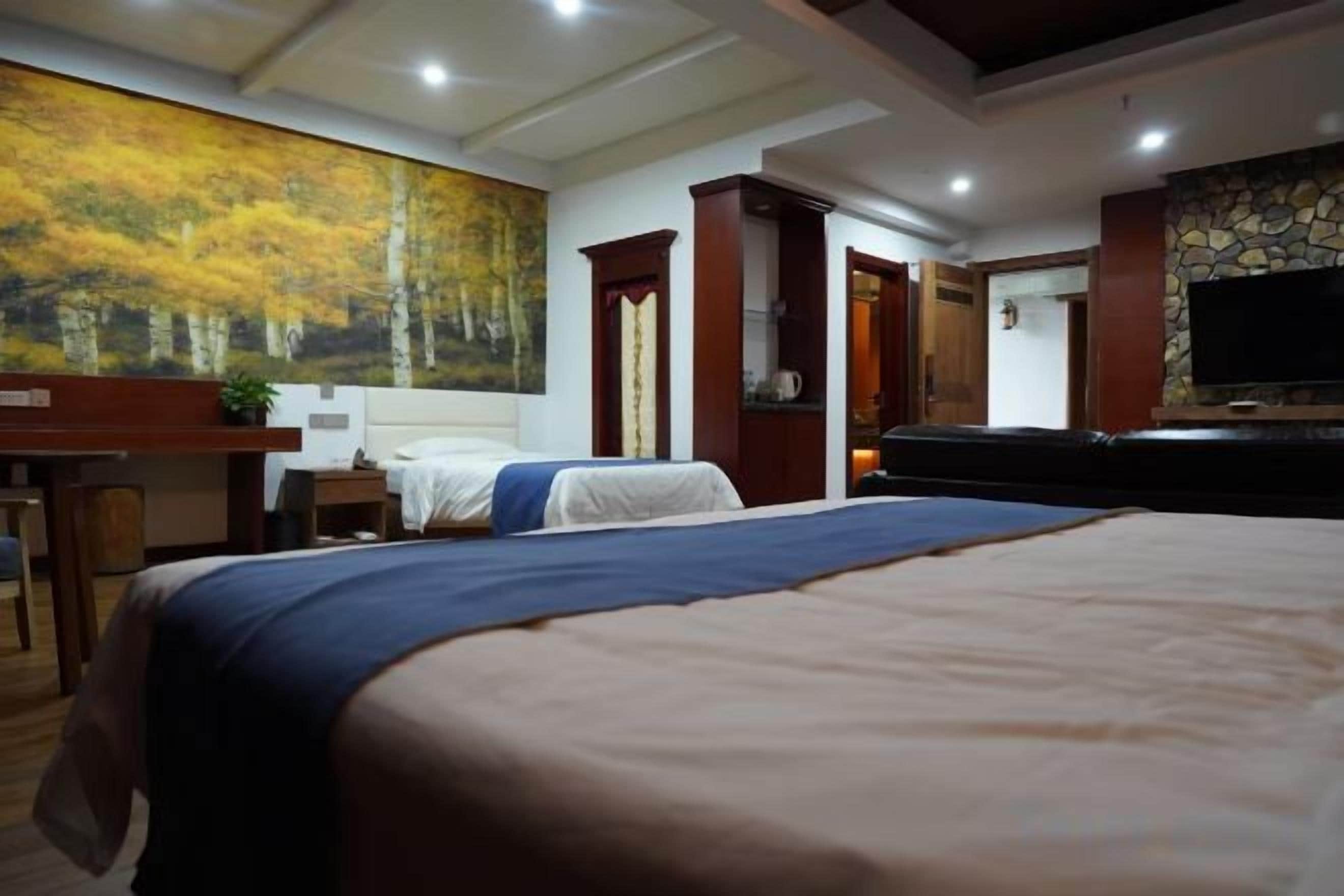 A hotel room with a large bed, a desk with a chair, a television, and a painting on the wall.