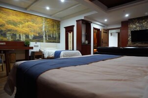 Una habitación de hotel con una cama grande, un escritorio con una silla, un televisor y un cuadro en la pared.
