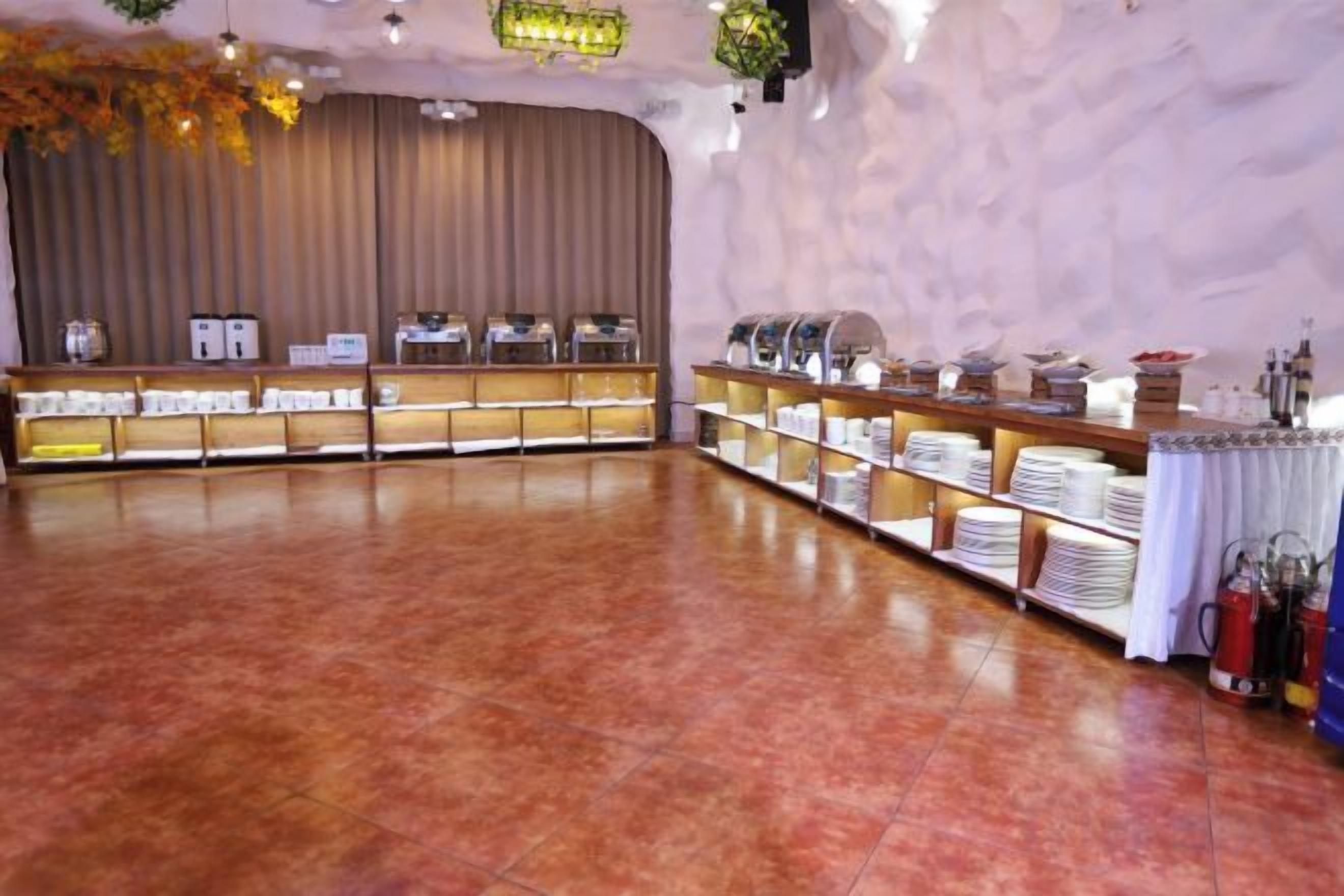 A spacious room with a long counter displaying various food items and a stage with curtains.