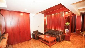 A living room with a sofa, armchair, coffee table, wooden flooring, and a sliding door. - Forest Snow Hotel (Genhe)