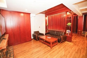 Una sala de estar con sofá, sillón, mesa de centro, piso de madera y puerta corrediza.