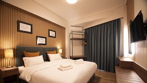 A hotel room with a large bed, bedside tables, a wall-mounted TV, and a coat rack. - Falireon Hotel (Palaio Faliro)