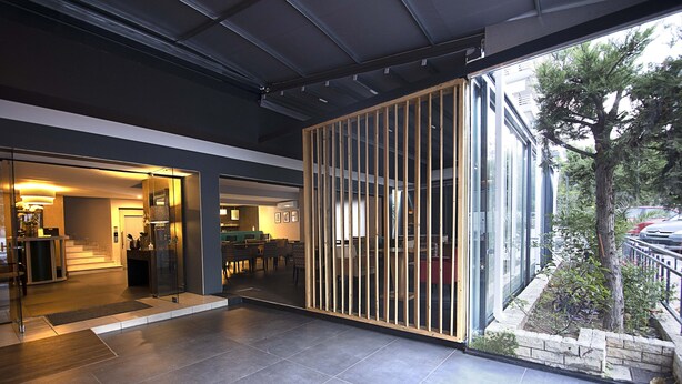 A modern interior with a glass partition, a staircase leading to another level, and a view of the outdoors. - Falireon Hotel (Palaio Faliro)