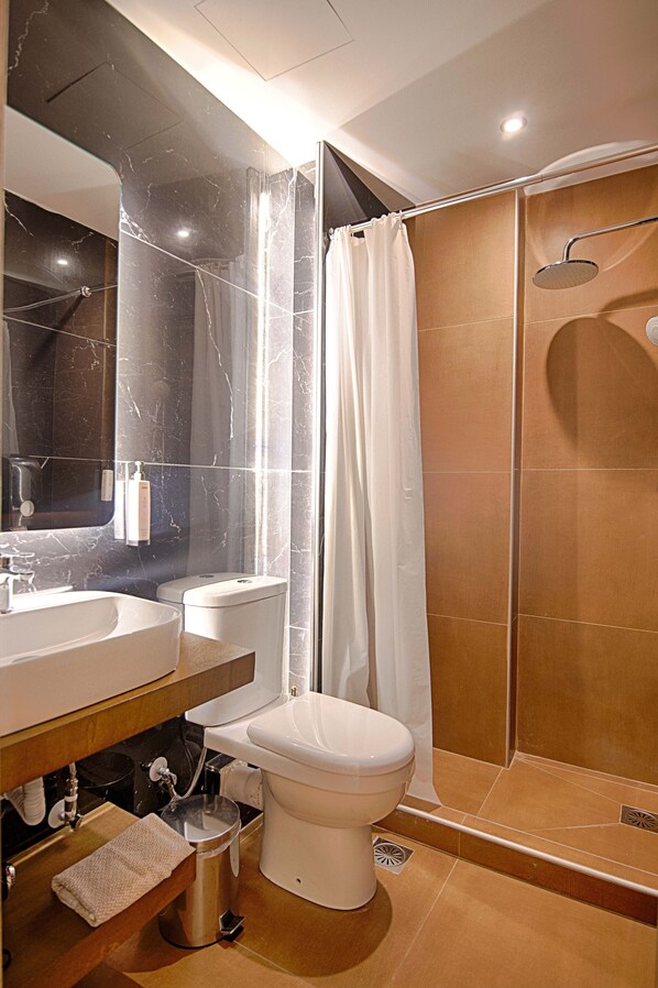 Un baño moderno con tocador de mármol, inodoro y cabina de ducha.