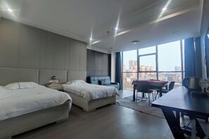 A modern hotel room with two beds, a dining table, and a view of the city. - Marriott Hotel (Shangrao)