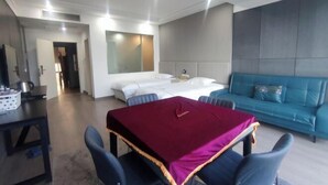 Ein modernes Hotelzimmer mit einem Bett, einem blauen Sofa, einem Esstisch mit Stühlen und einem großen Spiegel.