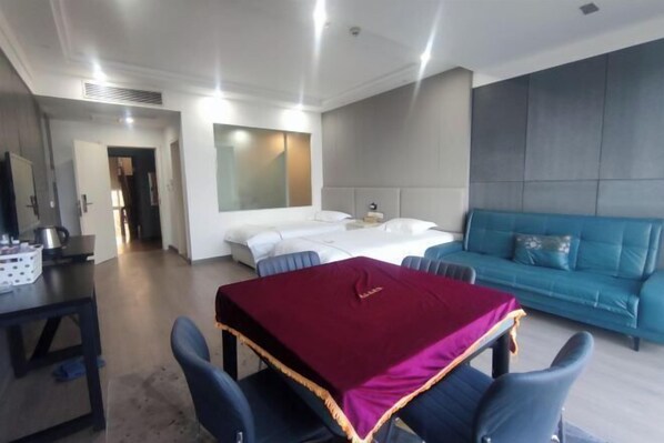 A modern hotel room with a bed, a blue sofa, a dining table with chairs, and a large mirror. - Marriott Hotel (Shangrao)