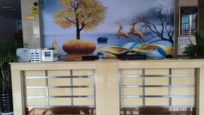 Ein Empfangstresen mit einer Wandmalerei von Baum, Reh, einer großen Pfirsichfrucht und einem Gewässer.
