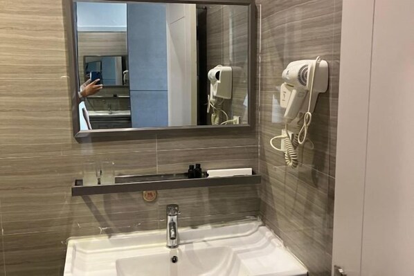 Ein Badezimmer mit einem großen Spiegel, einem Waschbecken und zwei an der Wand befestigten Haartrocknern.