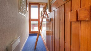 A narrow hallway with wooden paneling, a blue carpet, and a wooden ladder leaning against the wall. - Comfortable Apartment, Ski-in/Ski-out, Balcony, Wifi (Les Arcs 1800)