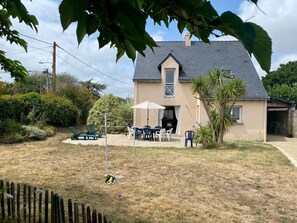 A house with a sloped roof, a covered patio with outdoor furniture, and a fenced yard. - Traditional house with garden and activities, quiet near the sea (La Baule)