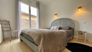 A bedroom with a bed, a chair, a nightstand, and a window with curtains. - Traditional house with garden and activities, quiet near the sea (La Baule)