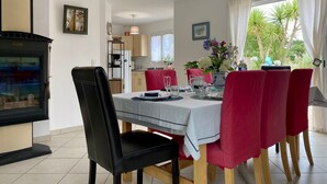 A dining area with a table set for four, red chairs, a black chair, a wooden table, and a hanging light fixture. - Traditional house with garden and activities, quiet near the sea (La Baule)